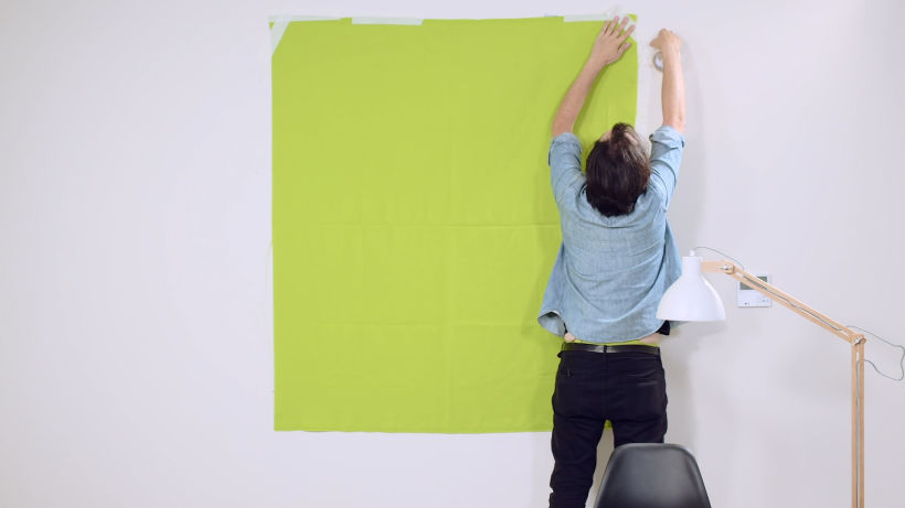 Pega la tela verde a la pared con cinta aislante