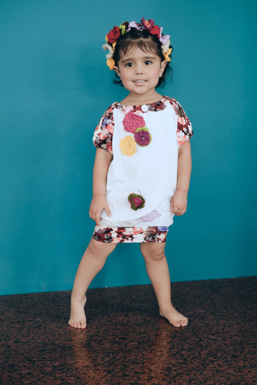 Vestido de niña elaborado a partir de una camiseta blanca de adulto, intervenida con retazos de tela y flores tejidas a mano