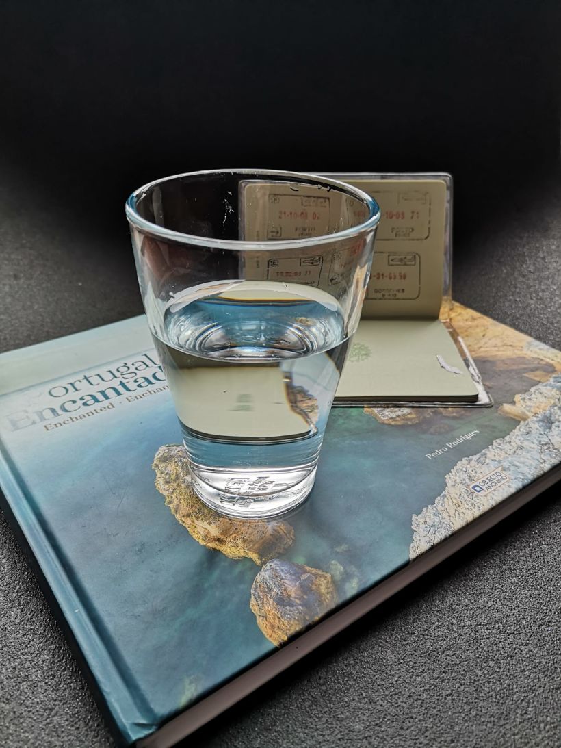 Um livro, o passaporte e o copo meio cheio. 