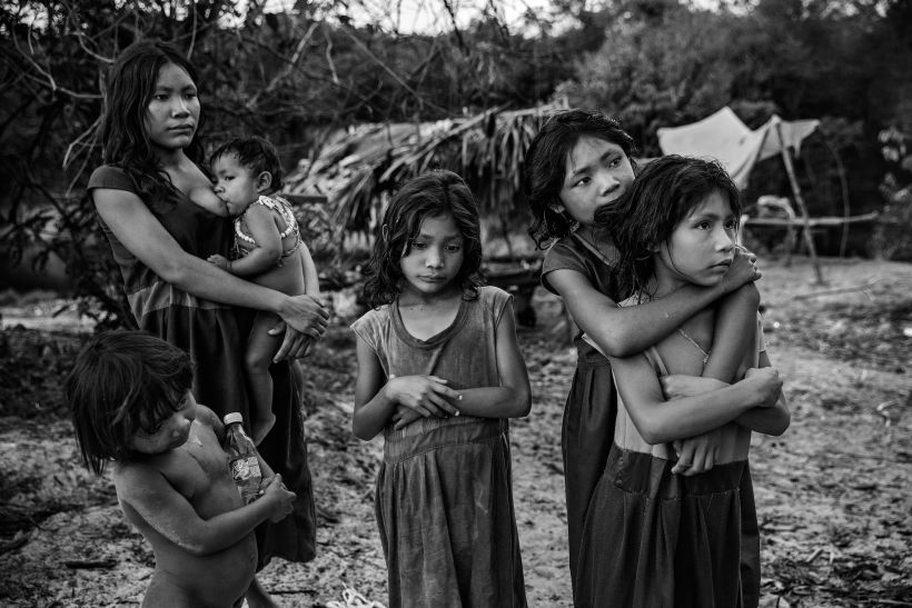 Women and children from the Pirahã community watch drivers passing on the Trans-Amazonian highway, Brazil. Lalo de Almeida.