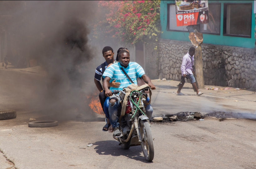 a biker crossing through burning tires with his parsanger in Port-au-Prince, Haiti,2024.(photo/ Pierre Marckinson)