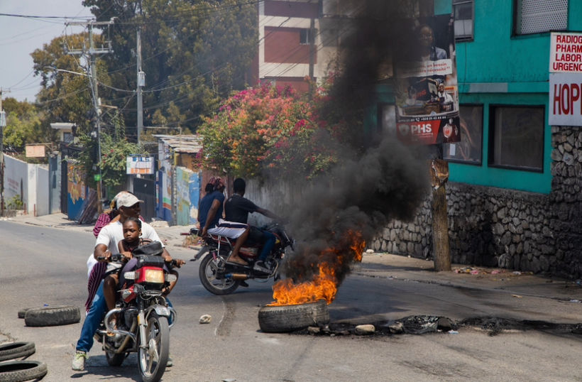 a biker crossing through burning tires with his parsanger in Port-au-Prince, Haiti, 2024. (Photo/Pierre Marckinson)