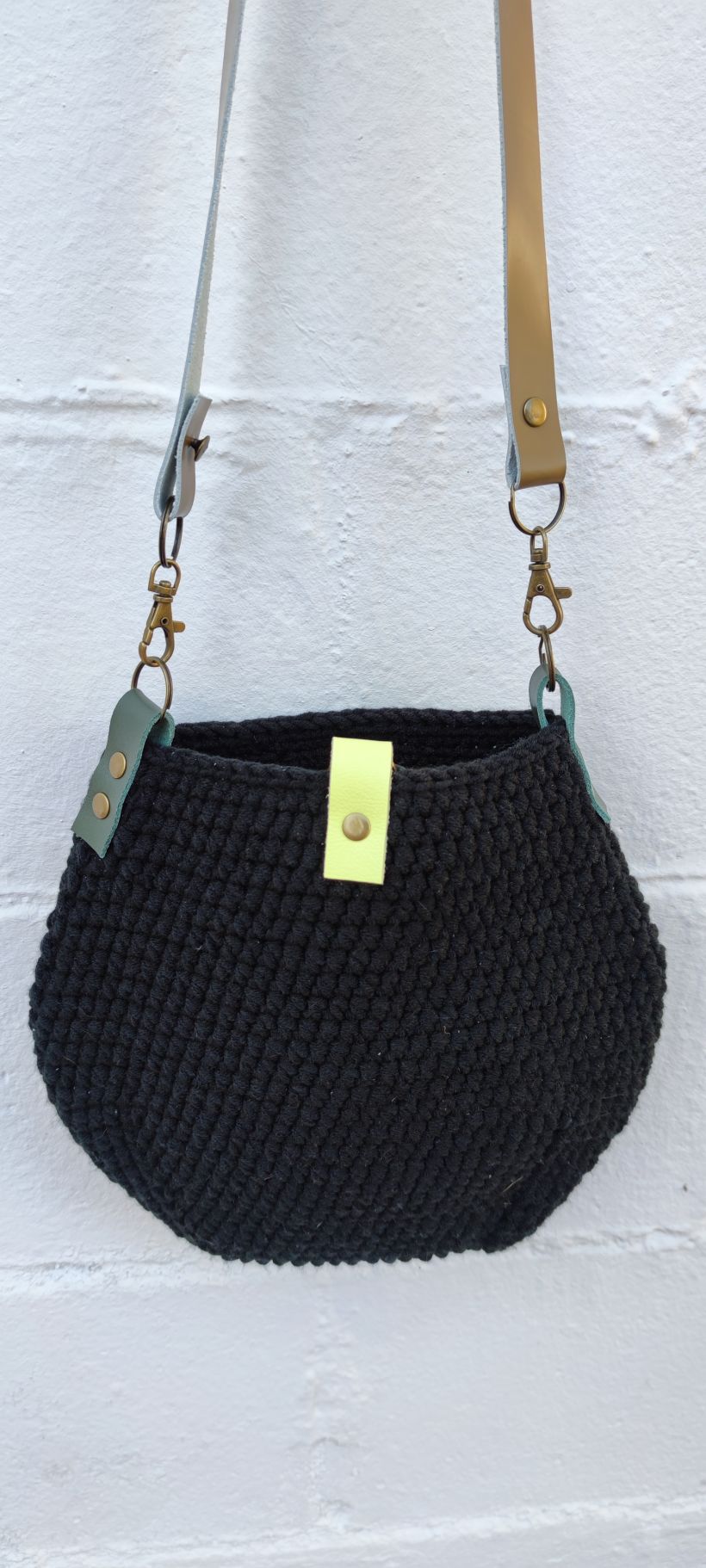 Bolso de algodón negro con asa de cuero para llevar en bandolera y un mosquetón para enganchar las llaves